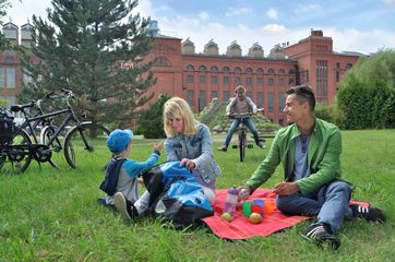 Familie beim Picknick vor dem Backsteinbau der Energiefabrik Knappenrode, die ihre Türen am 16. Oktober wieder für Gäste öffnet. Foto: Tourismusverband Lausitzer Seenland, Nada Quenzel
