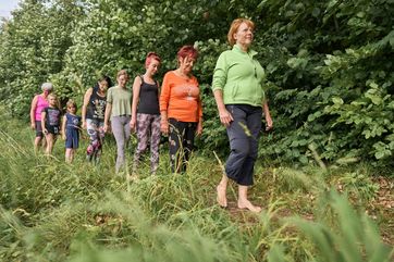 Barfuß gehen, Wildkräuter sammeln und Wasser treten: All das gehört zu einem Kneipp-Spaziergang im thüringischen Heilbad Bad Liebenstein mit Heilpraktikerin und Kräuterkundlerin Silke Grieger. Foto: Tino Sieland / Thüringer Heilbäderverband e.V.